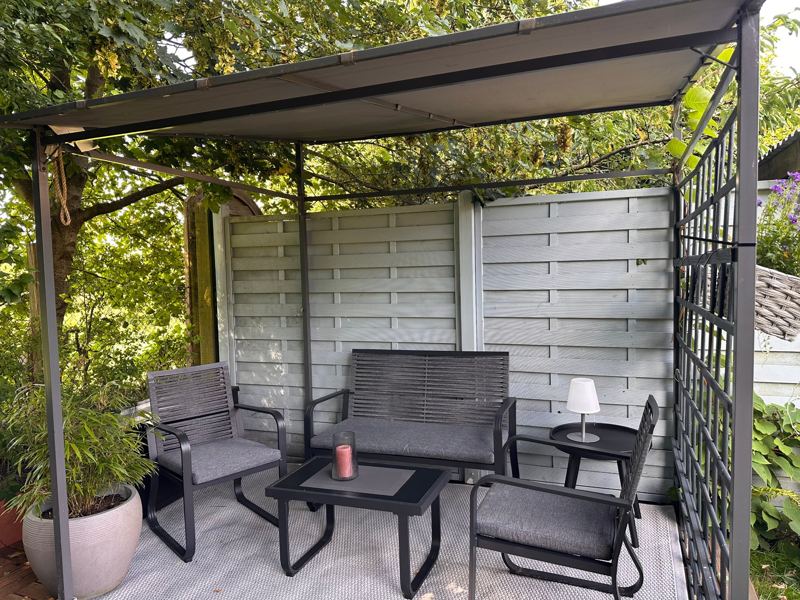 Überdachte Sitzecke mit Gartenmöbeln im Garten