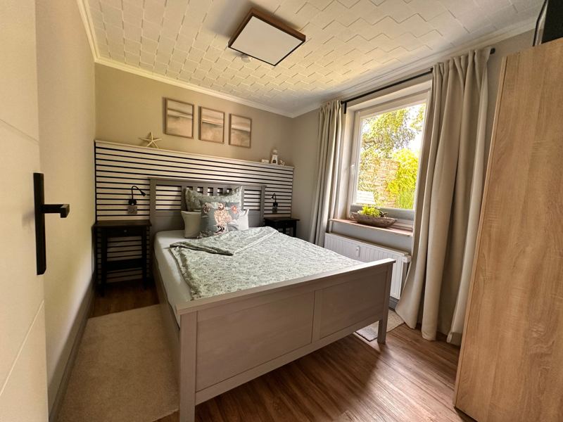 Schlafzimmer mit Doppelbett, Nachttischen und Fenster zum Garten