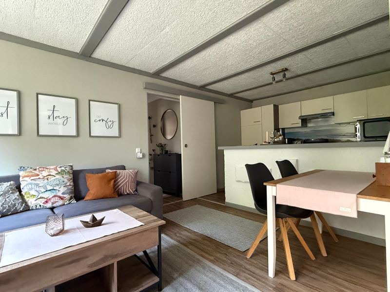 Wohnküche mit Sofa, Esstisch für zwei und Küchenzeile mit Tresen